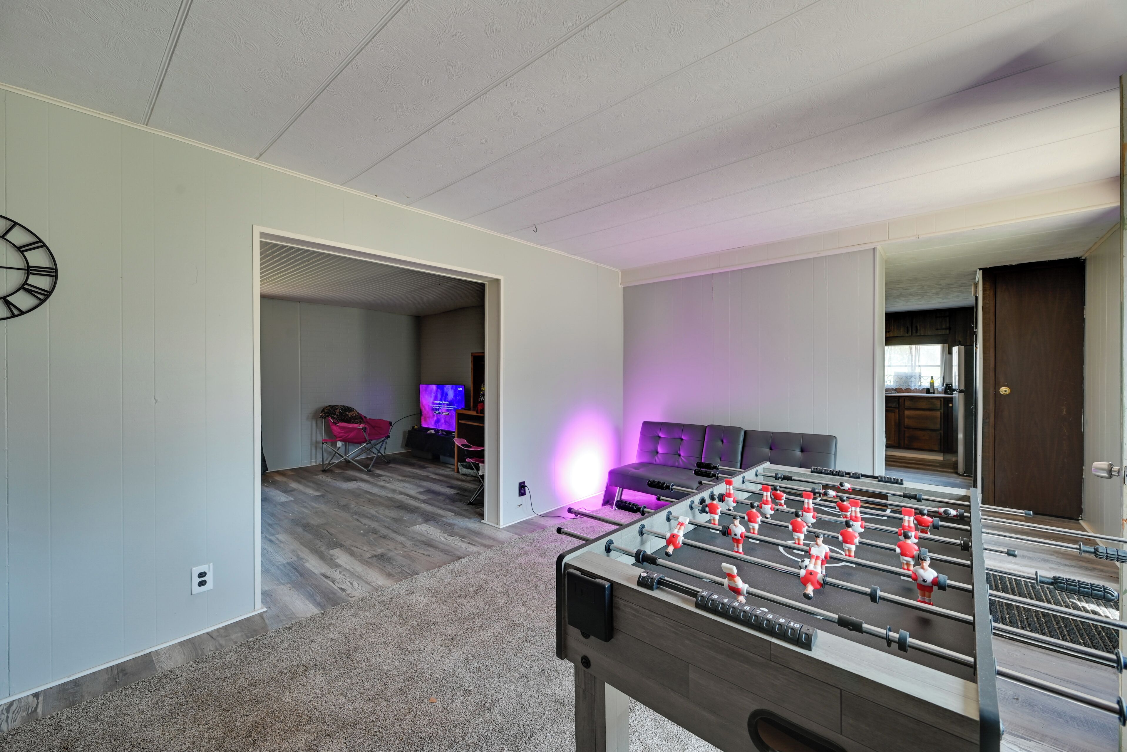A room with a foosball table, a TV, and a sofa.
