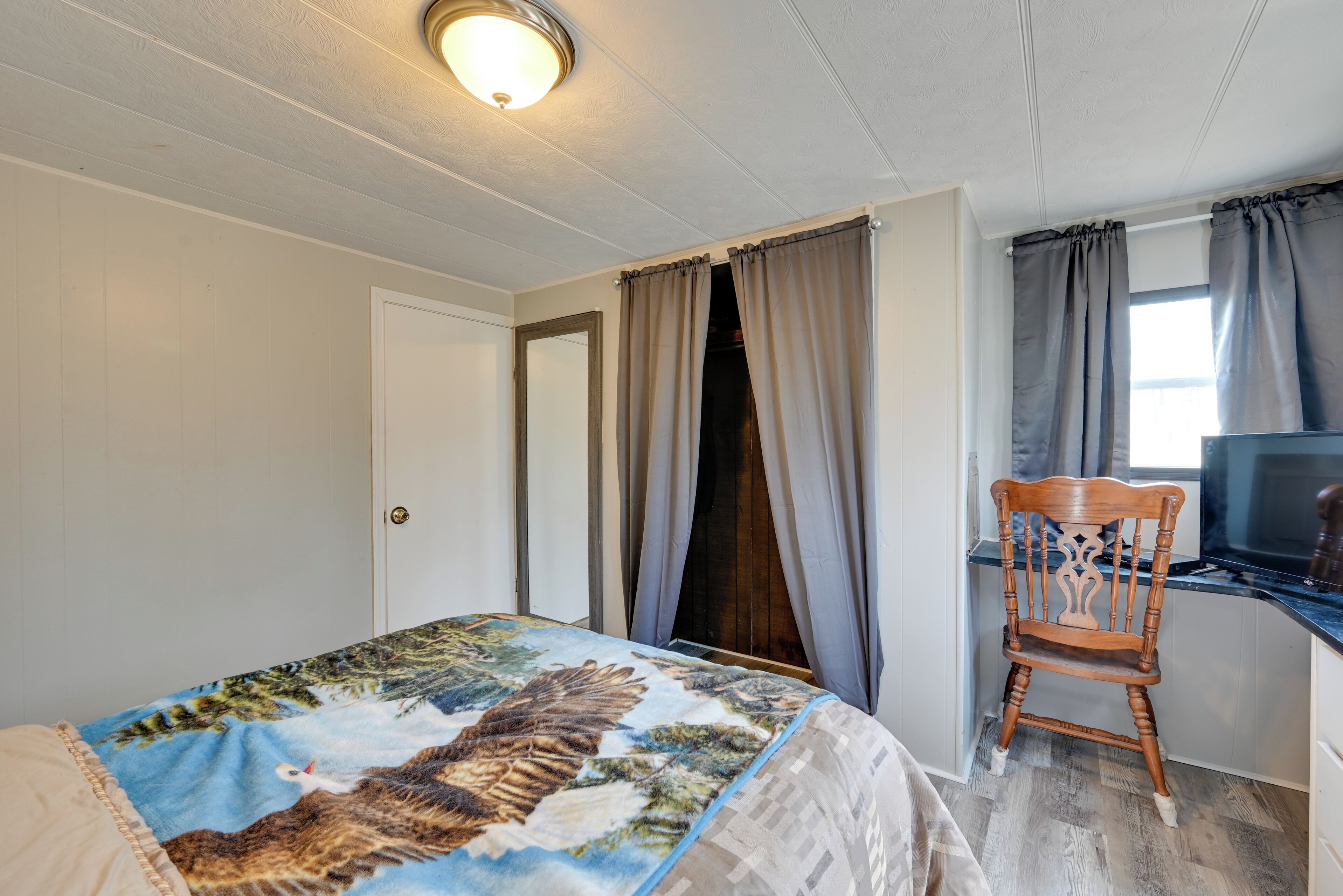 Un dormitorio con cama, una silla de madera, un escritorio y una televisión.