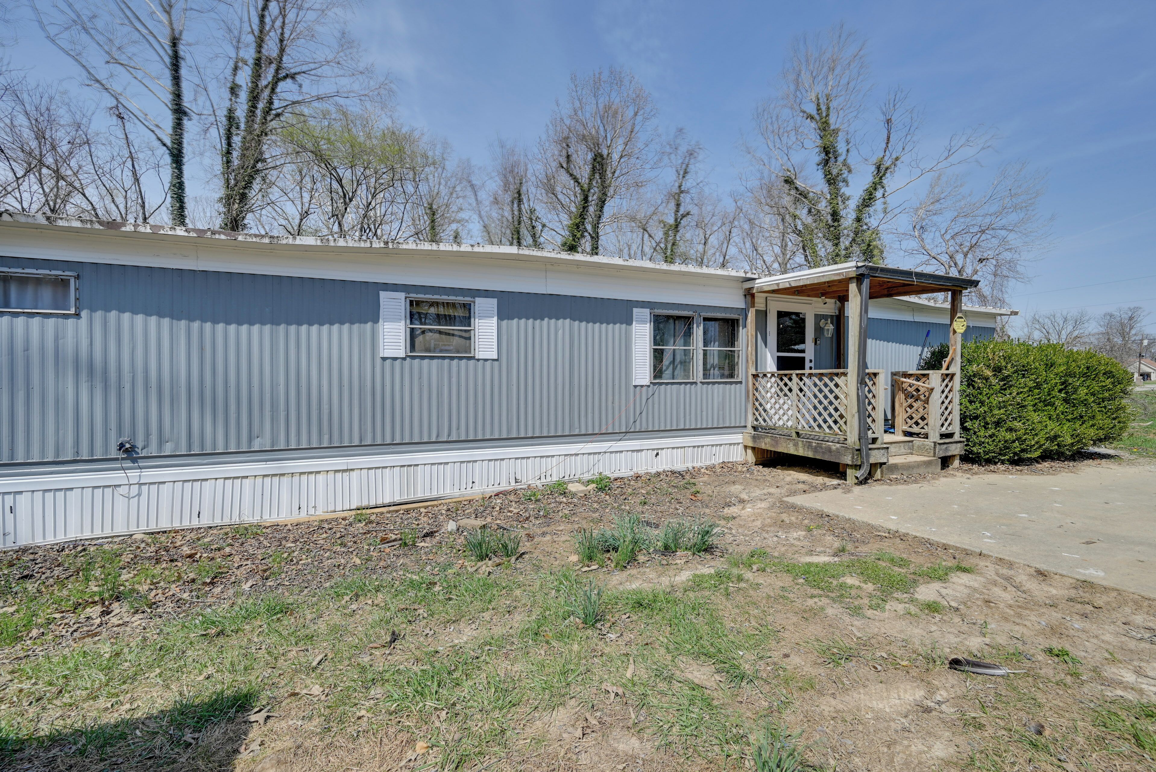 A mobile home with a covered porch and a small garden area.