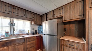 A kitchen with wooden cabinets, a stainless steel refrigerator, and a window with lace curtains. - 6 Mi to Fort Knox! Rural Family Home, Pets Welcome (Radcliff)