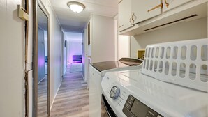 A laundry area with a front-loading washing machine, a dryer, and a white laundry basket. - 6 Mi to Fort Knox! Rural Family Home, Pets Welcome (Radcliff)