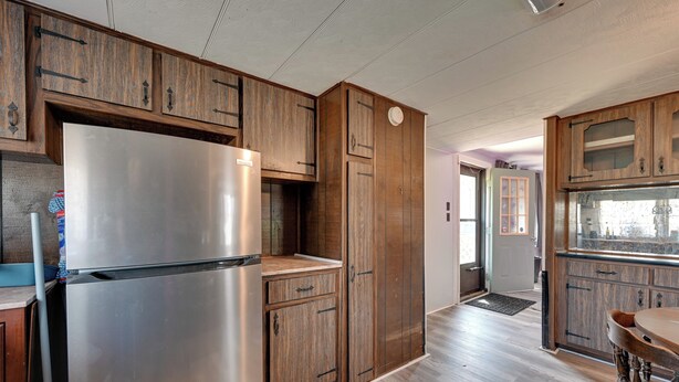 A kitchen with wooden cabinets, a stainless steel refrigerator, and a dining area with a wooden table and chairs. - 6 Mi to Fort Knox! Rural Family Home, Pets Welcome (Radcliff)