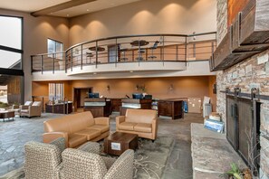 A spacious lobby with leather sofas, a fireplace, a reception desk, and a mezzanine with a balcony. - Remodeled, Steps to the Hot Tub | Sleeps 4 | Moose Mgt 527 (Park City)