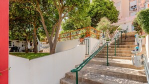 Eine Treppe mit grünen Handläufen, die zu einer weißen Wand führt.