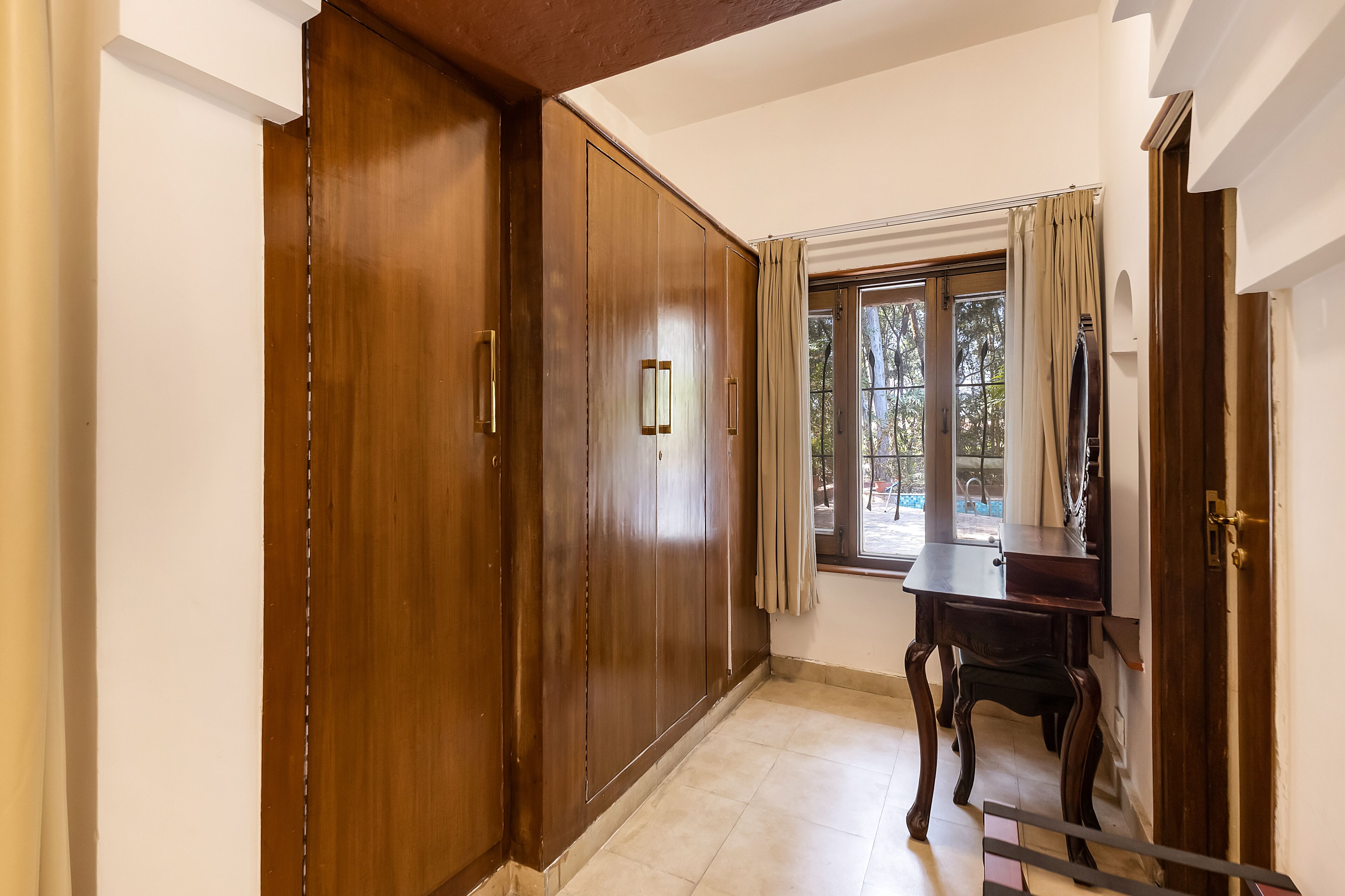 Un couloir avec des armoires en bois, un bureau en bois et une fenêtre avec des rideaux.