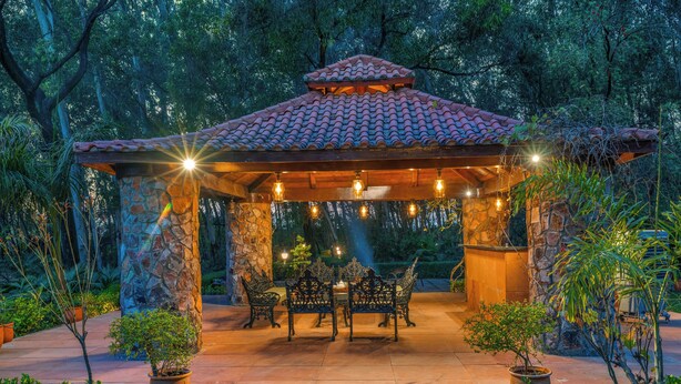 Un gazebo con colonne in pietra, tetto in tegole e posti a sedere all'aperto.