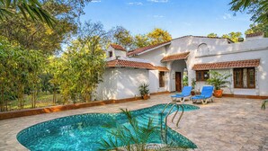 Una piscina con acqua cristallina, circondata da una zona prendisole con lettini e piante in vaso.
