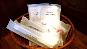A basket containing various personal care items including cotton body towel, razor, hair brush, and toothbrush. - Island Village Ishigaki-jima (Ishigaki)