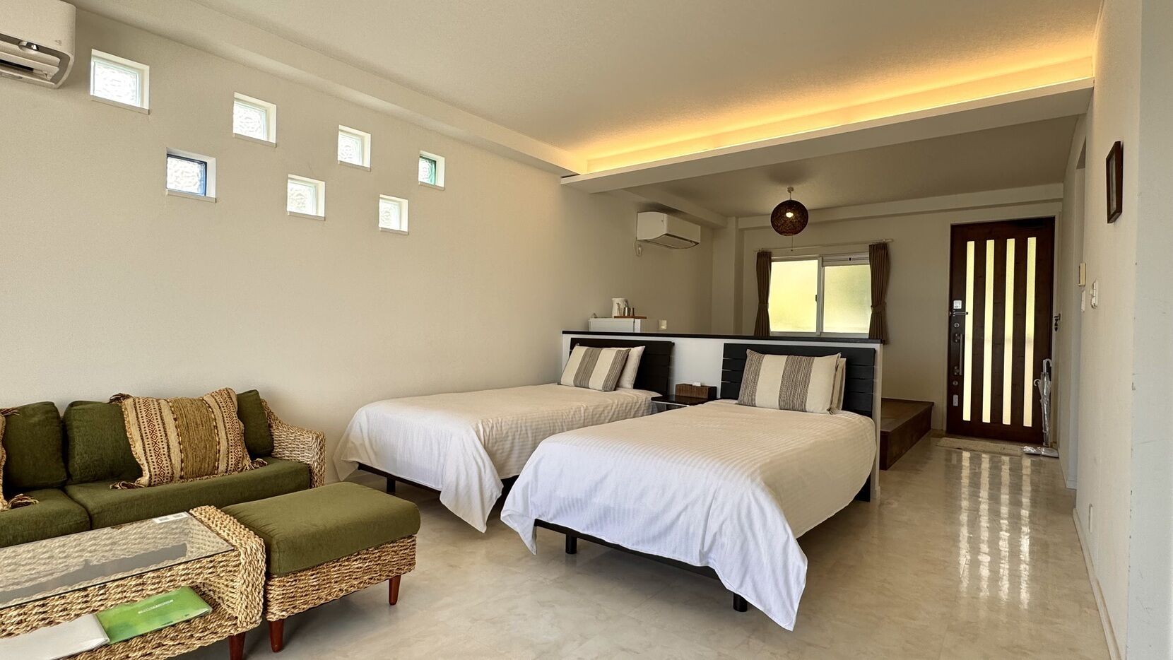 Ein Hotelzimmer mit zwei Betten, einem Sofa, einem kleinen Tisch und einem Fenster mit Vorhängen.