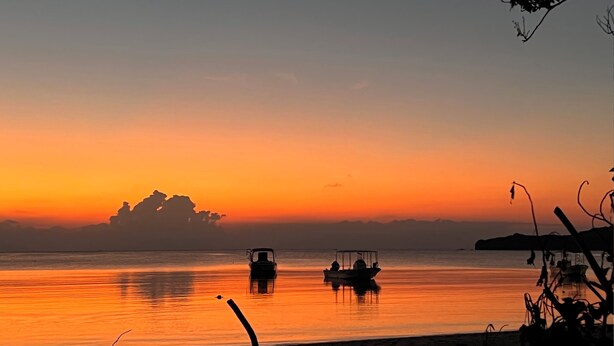 A calm lake at sunset with boats and distant land silhouettes. - Island Village Ishigaki-jima (Ishigaki)