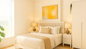 A bedroom with a bed, bedside tables, lamps, a hanging plant, and a painting on the wall. - Chic 2BR in Shoreditch Prime Location (London)