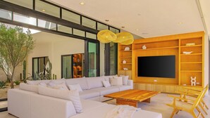 Een moderne woonkamer met een hoekbank, een houten salontafel en een ingebouwde tv-kast.