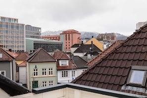 Een stadsgezicht met een mix van moderne en traditionele gebouwen, waaronder een opvallend roze gebouw en een groene constructie met een schuin dak.