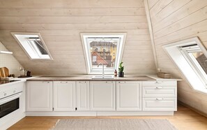 Een moderne keuken met witte kasten, een centraal eiland, dakramen en uitzicht op de stad.