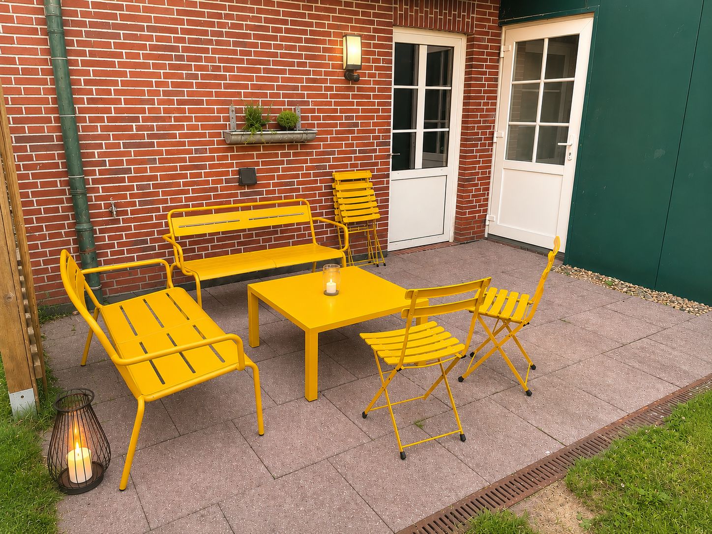 A patio with yellow metal furniture, a brick wall, a door, and a green wall.