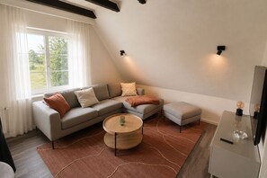 Un saló modern amb un sofà seccional, una taula de centre rodona i una taula auxiliar amb tapa de vidre.