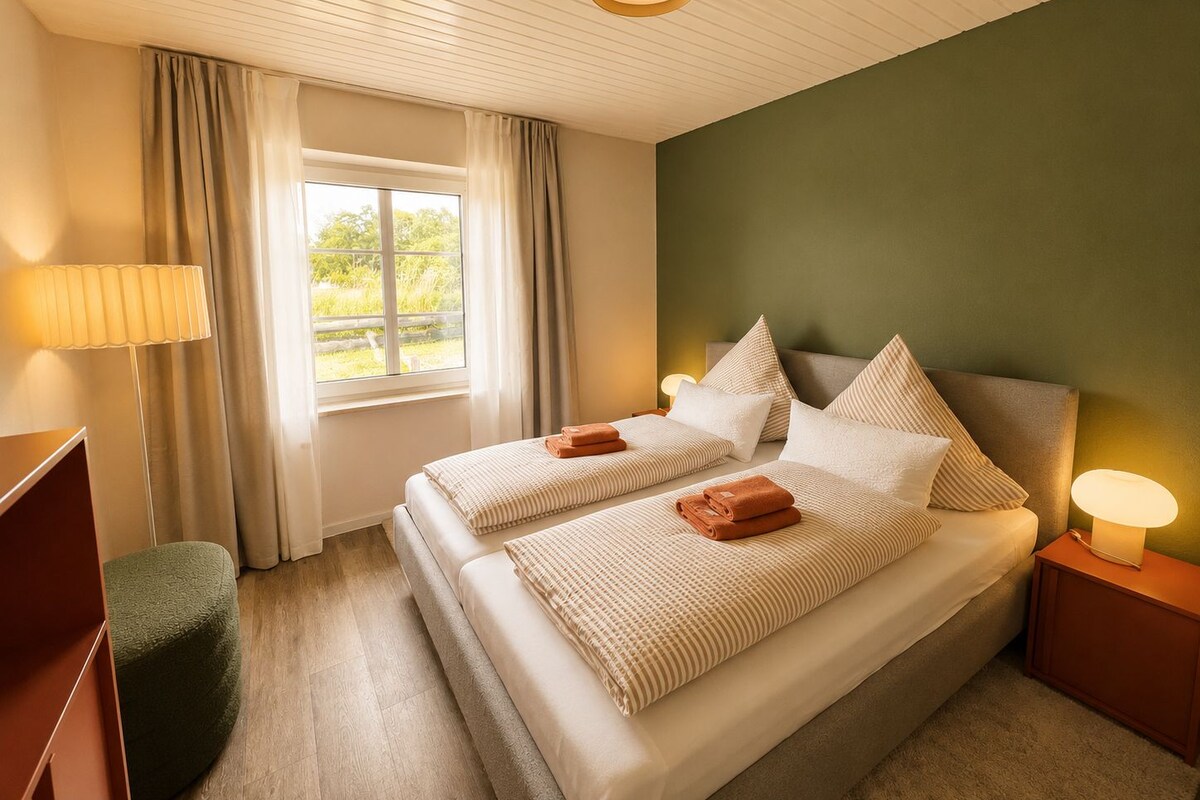 Una camera d'albergo con un letto, due lampade ai lati, una scrivania e una finestra con tende.