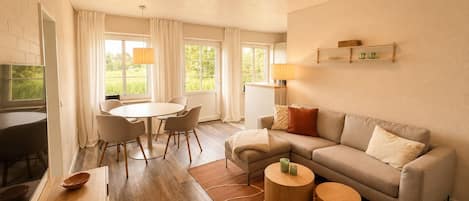 A modern living room with a sofa, a dining table with chairs, and a TV.
