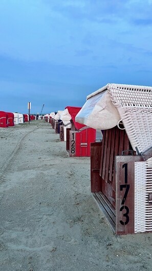 Una fila di cabine balneari numerate 172, 173 e 128, con un sentiero sabbioso che conduce alla spiaggia.