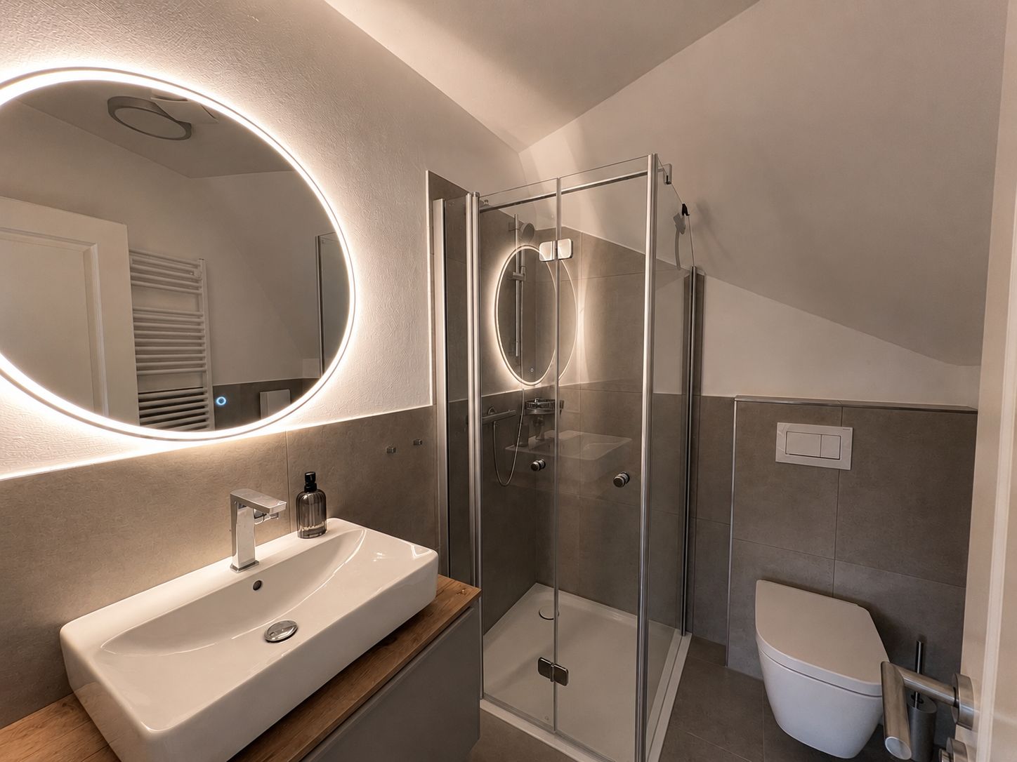 Une salle de bain moderne avec un grand miroir, un lavabo, une douche à parois de verre et des toilettes.