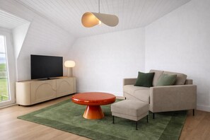 A modern living room with a television, sofa, round table, and a ceiling light. - elf-36 (Esens)