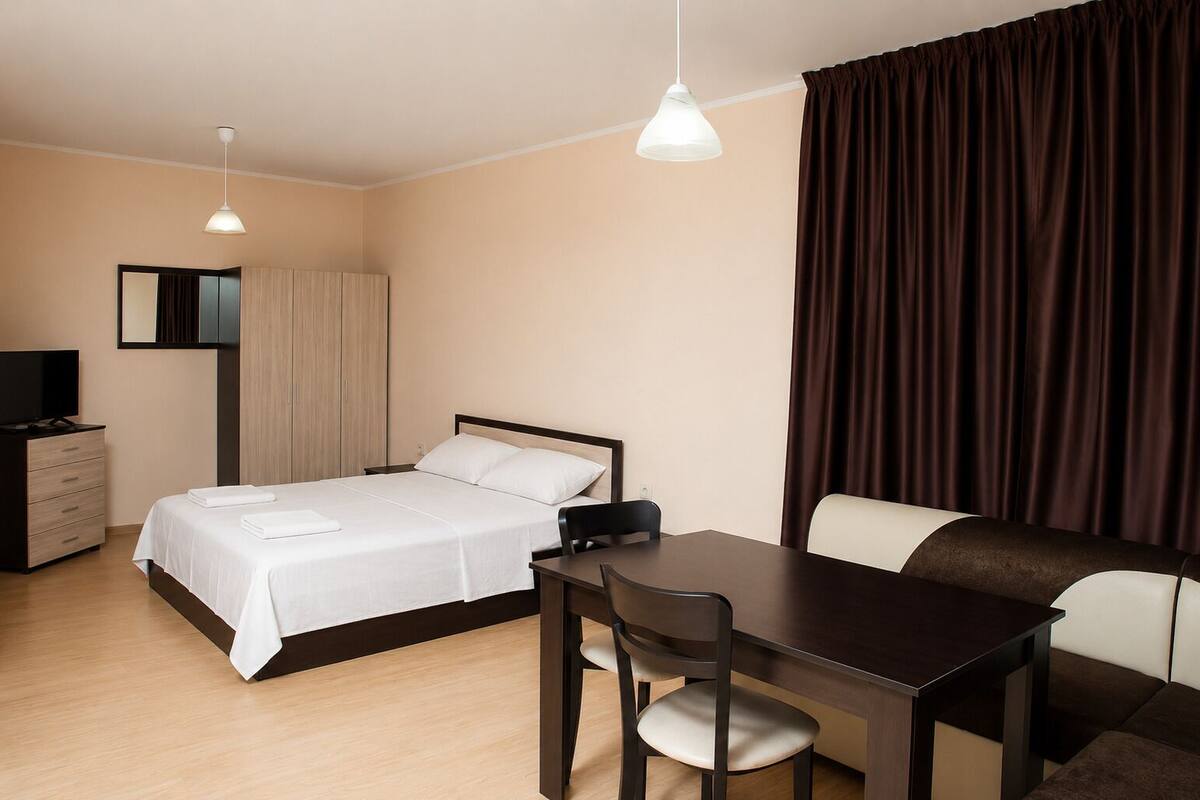 A hotel room with a bed, a desk, a chair, a television, and a wardrobe.