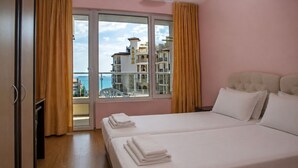 A hotel room with two beds, a balcony, and a view of a building with 'ARTUR' on it. - Anthony Complex (Sveti Vlas)