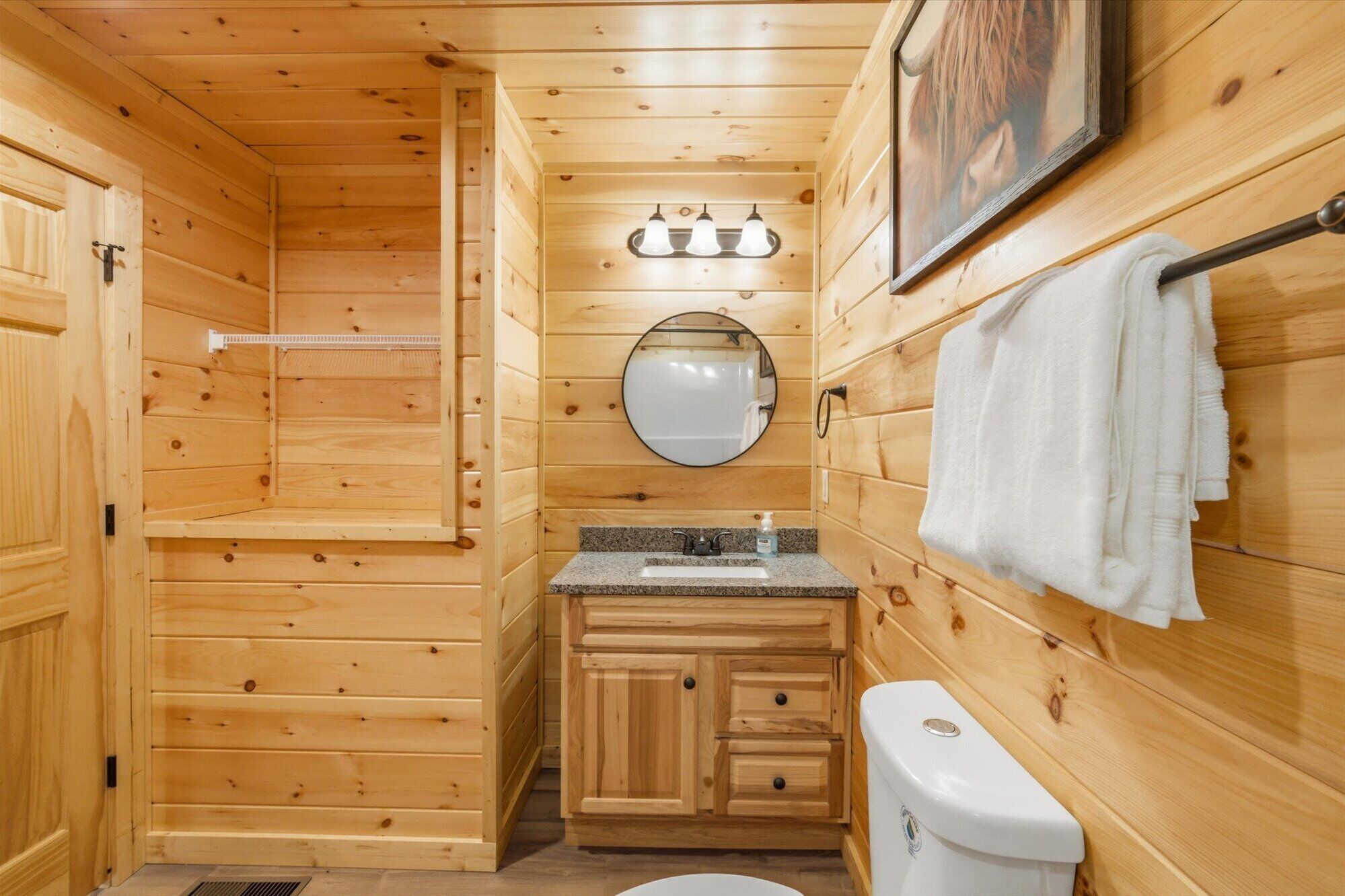Un baño de cabaña de madera con lavamanos, espejo, toallero y retrete.