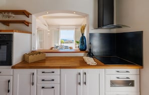 A modern kitchen with wooden countertops, a built-in oven, and a view of the outdoors. - La Cabanette – Villa with pool and seaview (Tourrettes-sur-Loup)