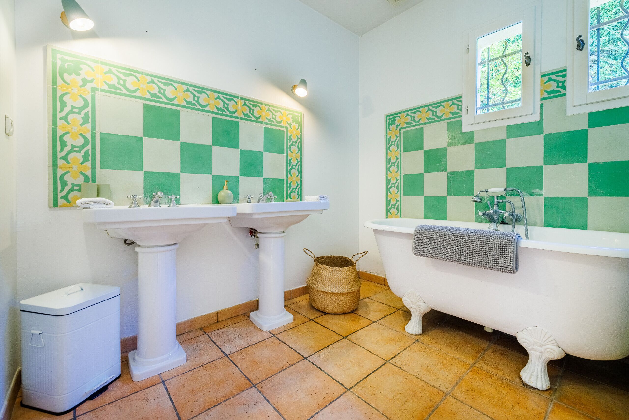 A bathroom with two sinks, a bathtub, and a window.