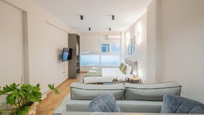 Ett modernt hotellrum med en soffa, en tv, en säng med utsikt och en växt.