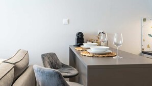 Ett modernt kök med en matplats, inklusive en soffa, stolar, en kaffemaskin och ett vinglas.