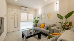 A modern living room with a sofa, coffee table, and potted plants. - Modern Prime Location Apt in Thessaloniki Center (Thessaloniki)