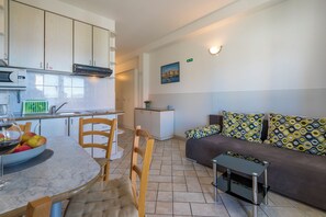 A compact living space with a kitchen, dining area, and a sofa with patterned cushions. - Beautiful apartment in a quiet residential area in Crikvenica (Crikvenica)