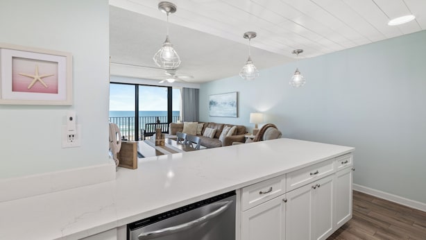 A modern kitchen with white cabinetry, a built-in dishwasher, pendant lighting, and a view to the outside. - Island Sunrise 464 by Liquid Life (Gulf Shores)