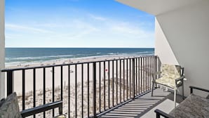 A balcony with a view of the beach, a chair, and a table. - Island Sunrise 464 by Liquid Life (Gulf Shores)
