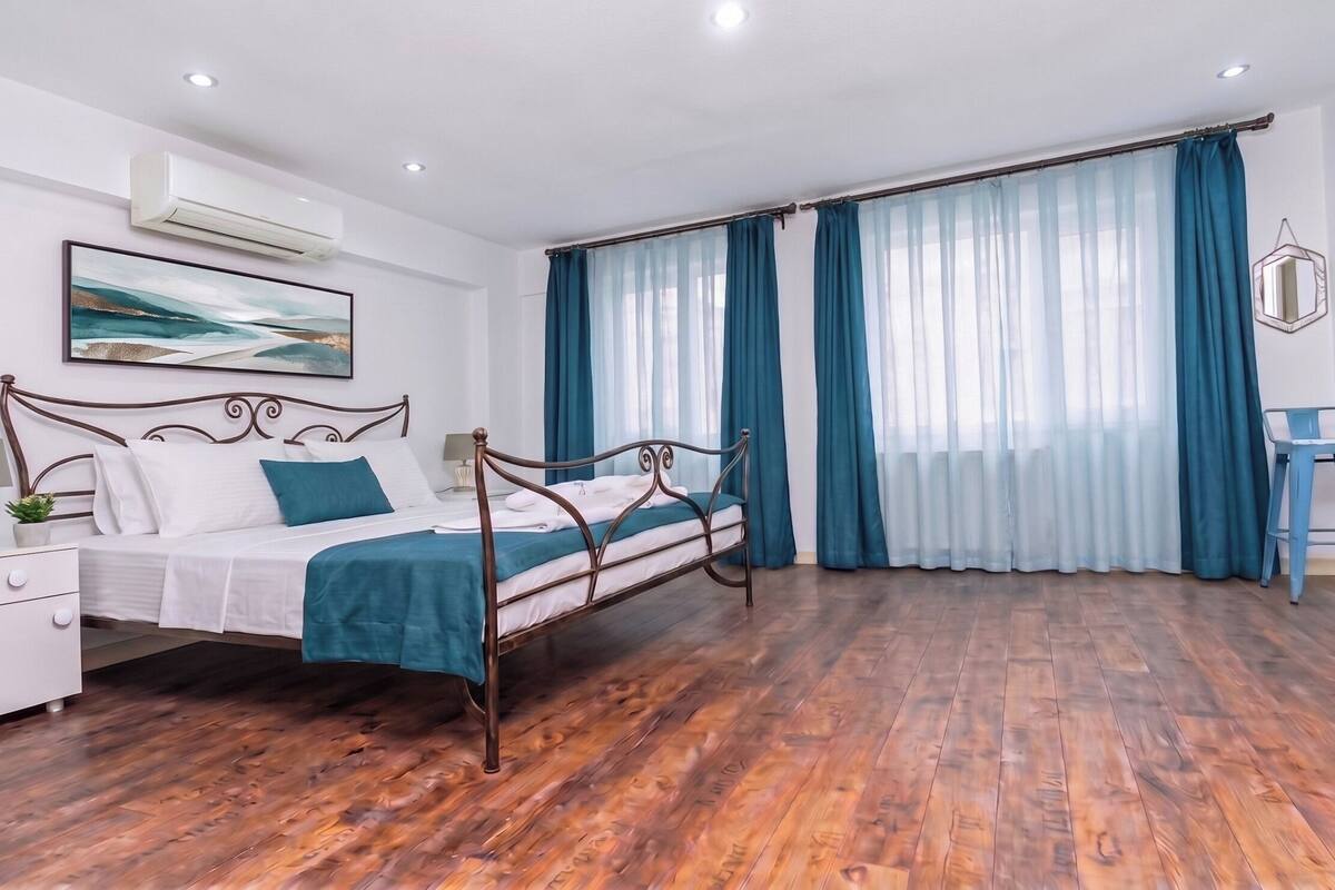 A bedroom with a bed, a nightstand, a lamp, a chair, and a window with curtains.