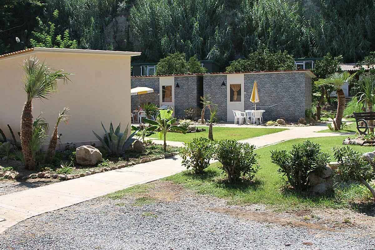 A courtyard with a building, outdoor seating, and greenery.
