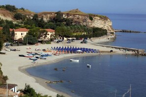 A coastal beach with boats, umbrellas, and buildings. - FRUIT VILLAGE Baia delle Sirene (Briatico)