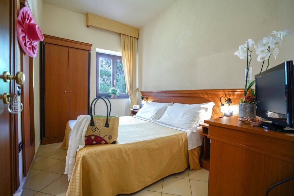 A hotel room with a bed, a TV, a desk, and a wardrobe.