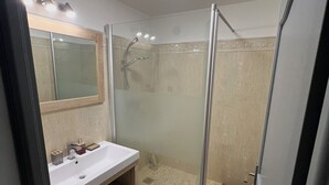 A bathroom with a glass-enclosed shower, a vanity with a mirror, and a tiled floor. - Paris La defense - Apartment 3 bedrooms (Courbevoie)