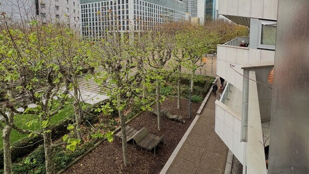A modern building with a pathway, trees, and a distant cityscape. - Paris La defense - Apartment 3 bedrooms (Courbevoie)
