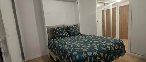 A bedroom with a bed, a wardrobe, and a mirror.