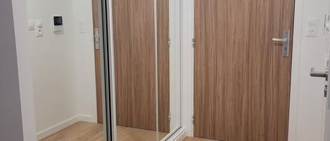 A room with a sliding glass door, wooden flooring, and a white door with a handle.