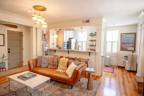 Ein Wohnzimmer mit braunem Ledersofa, einem Couchtisch und einer Küchenzeile mit Kühlschrank und Mikrowelle.
