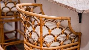 A bar area with wicker chairs, a marble countertop, and a kitchen in the background. - Charleston Charm: Cozy 1BR Apartment with Patio (Charleston)