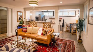 A living room with a leather sofa, a glass coffee table, and a red patterned rug. - Charleston Charm: Cozy 1BR Apartment with Patio (Charleston)