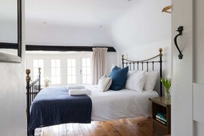 Ein Schlafzimmer mit Bett, Nachttisch, Fenster und Blick nach draußen.