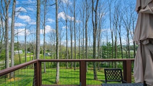 A wooden deck with a metal railing, a table, and a chair. - Modern Upper Retreat w Free Tix Deck 2 Suites (Hendersonville)