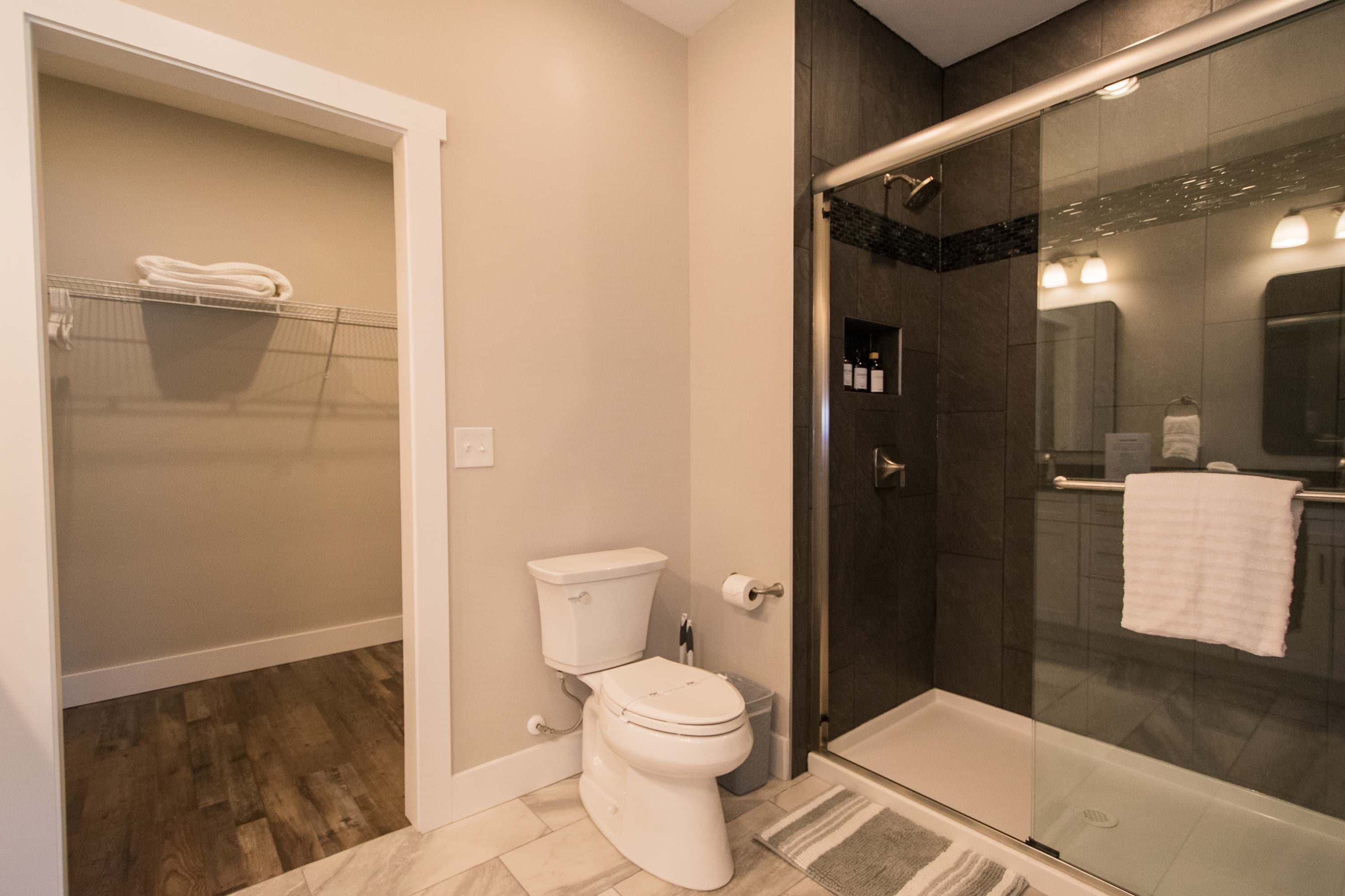 A bathroom with a toilet, a glass shower enclosure, and a towel rack.